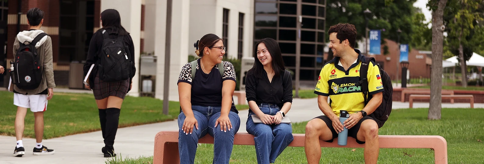 students sitting and talking on campus bench